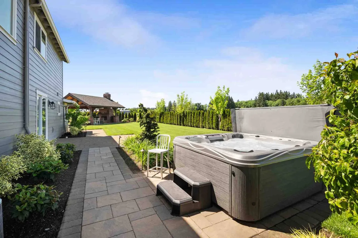 An inviting outdoor area featuring a hot tub, beautifully landscaped garden, and spacious patio. The space is perfect for both relaxation and entertaining, with plenty of room for guests—and pets—to enjoy the grounds.