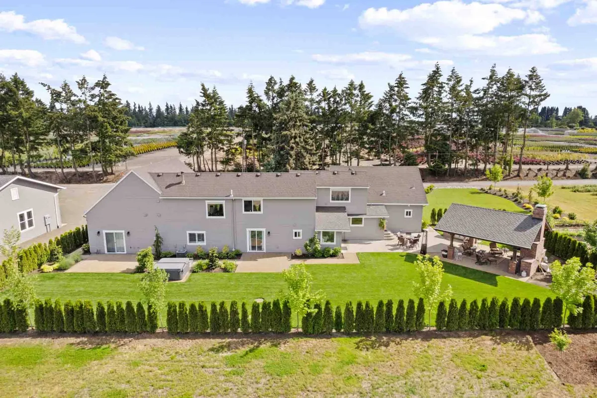 A tranquil exterior setting featuring a spacious lawn, an outdoor seating area, and a pathway leading to a gazebo. The surrounding trees add privacy and a peaceful atmosphere, perfect for outdoor gatherings or moments of relaxation between celebrations.