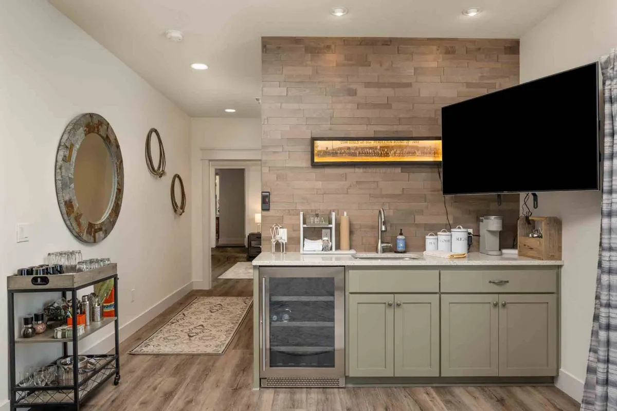 A cozy kitchenette area complete with mirrors, artwork, and a TV, designed for intimate meals or light cooking, reflecting the private amenities of the primary suite.
