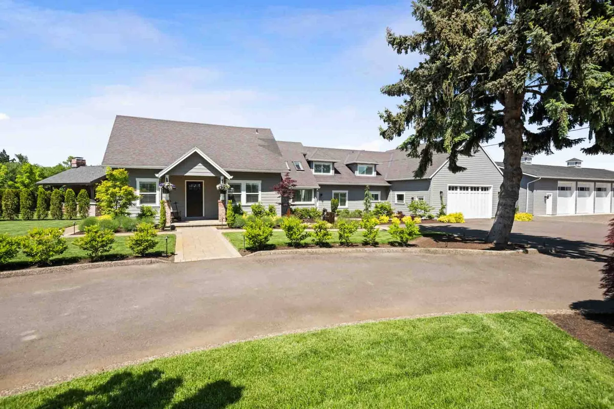 A view of the main entrance of the house, featuring a landscaped garden and a driveway leading up to the home. The setting is inviting and hints at the spaciousness and serene estate environment, ideal for guests arriving for special events.