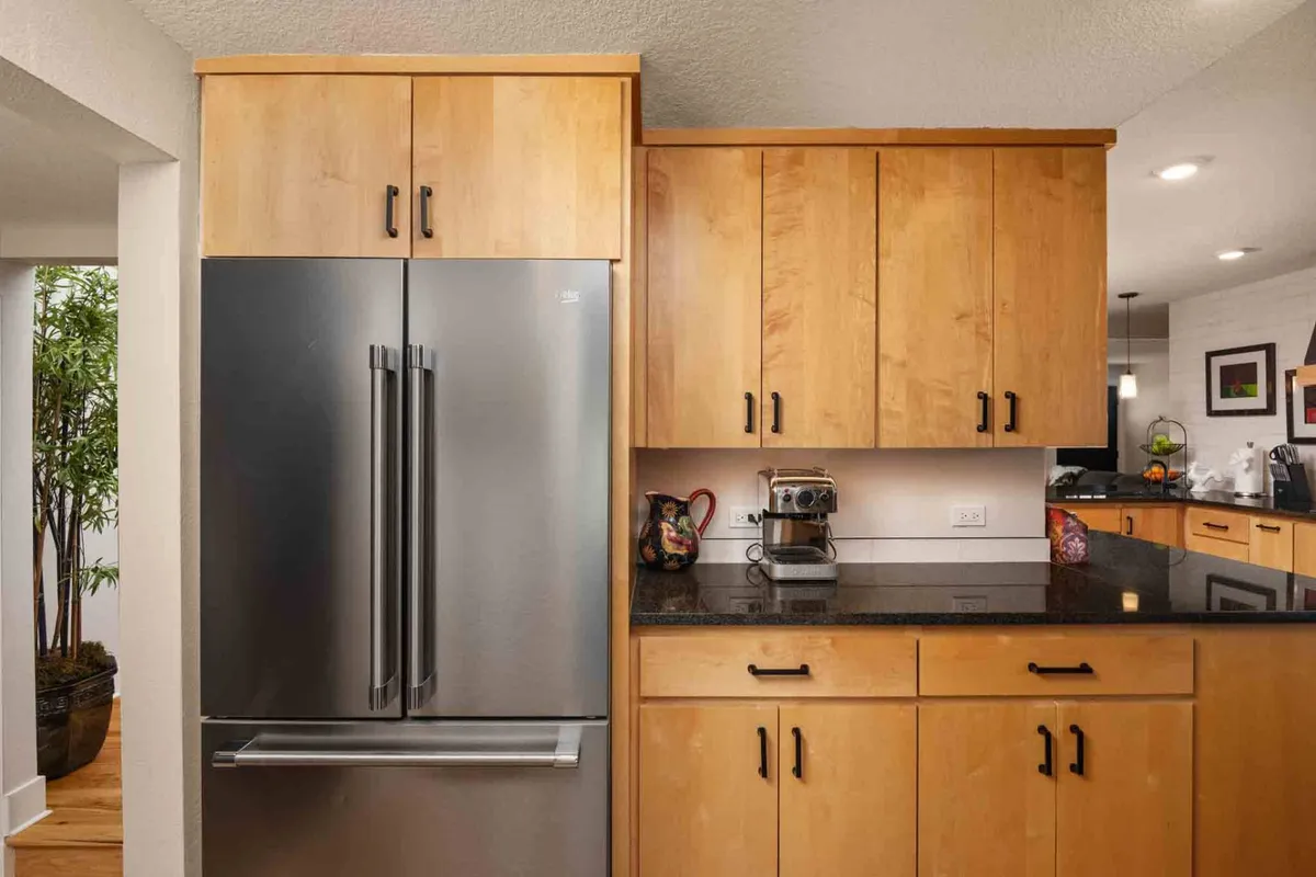 A modern, functional kitchen with stainless steel appliances, wooden cabinetry, and a granite countertop. The scene exudes convenience and warmth, perfect for group meal prep or casual gatherings.