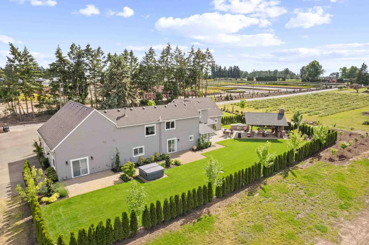 This exterior image features a well-maintained lawn bordered by outdoor seating areas, surrounded by mature trees and open landscape. The presence of both greenery and a furnished patio suggests ample space for outdoor relaxation, play, and gatherings, ideal for families and their pets. The scene conveys a sense of peacefulness and connection to nature—perfect for letting pets roam and enjoy the outdoors.