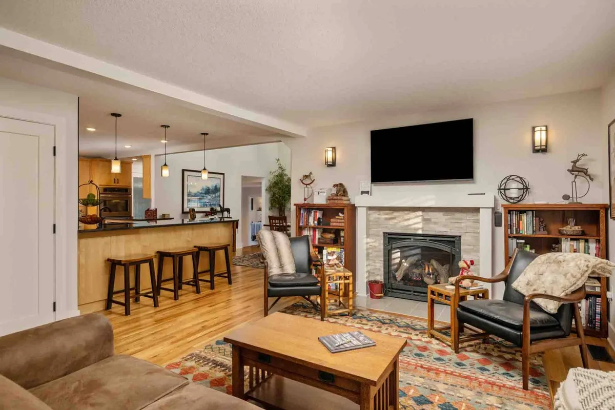 The image showcases a beautifully appointed living area with a crackling fireplace, built-in bookshelves filled with inviting reads, and a stylish, comfortable seating arrangement perfect for gathering. The mood is warm and welcoming, encouraging relaxation and connection.