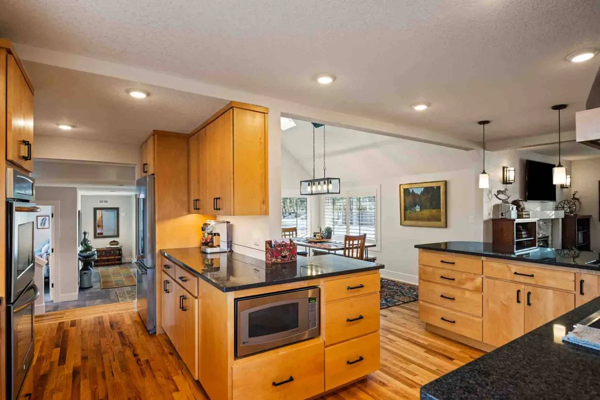 A bright, modern kitchen with a spacious island countertop, sleek stainless steel appliances, and rich wooden cabinetry. The open layout clearly connects to adjacent living and dining spaces, while the island serves as a hub for gathering and casual conversation.
