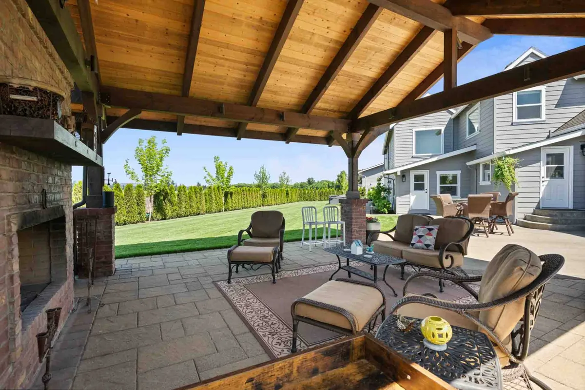 This image shows a welcoming outdoor seating area with a fireplace, surrounded by a well-manicured lawn and the back of the house. The space is set up for gatherings, relaxation, and socializing, making it ideal for groups attending events or weddings.